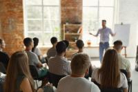 Menschen sitzen auf Stühlen in einem Seminar