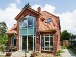 Einfamilienhaus mit Klinkerfassade und türkisfarbenen Holzfenstern von PaX