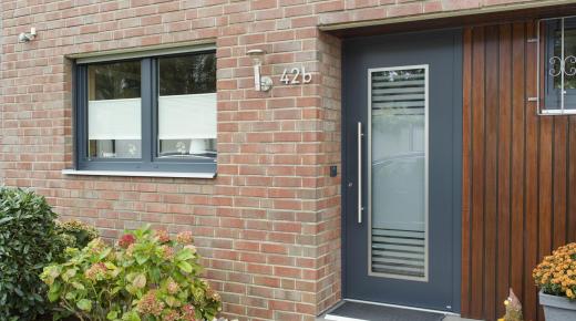 Anthrazitgraue Kunststofffenster und Aluminium-Haustür integrieren sich wunderbar in die Klinkerfassade