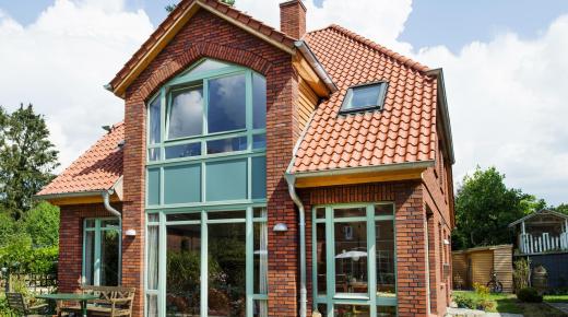 Einfamilienhaus mit Klinkerfassade und türkisfarbenen Holzfenstern von PaX