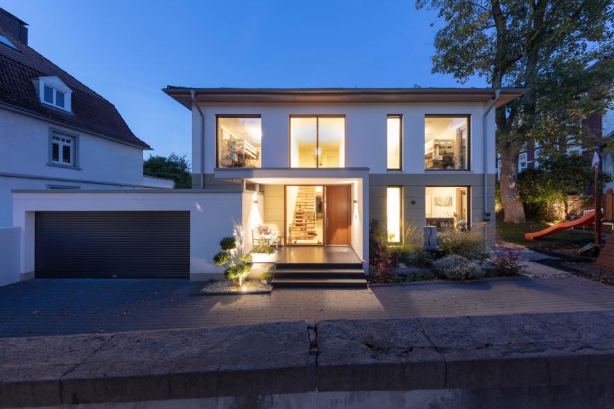 Die Stadtvilla mit Holz-Aluminium-Fenstern und Holzhaustür von PaX im Abendlicht