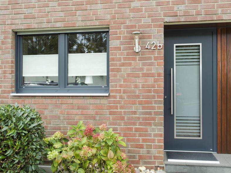Die anthrazitgrau folierten Kunststofffenster wurden farblich auf die Haustür abgestimmt