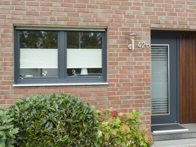 Zweiflügeliges Fenster mit anthrazitgrauem Kunststoffrahmen mit farblich abgestimmter Haustür