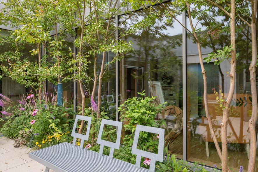 Die Bepflanzung im Innenhof harmoniert gut mit den Holz-Aluminium-Fenstern von PaX