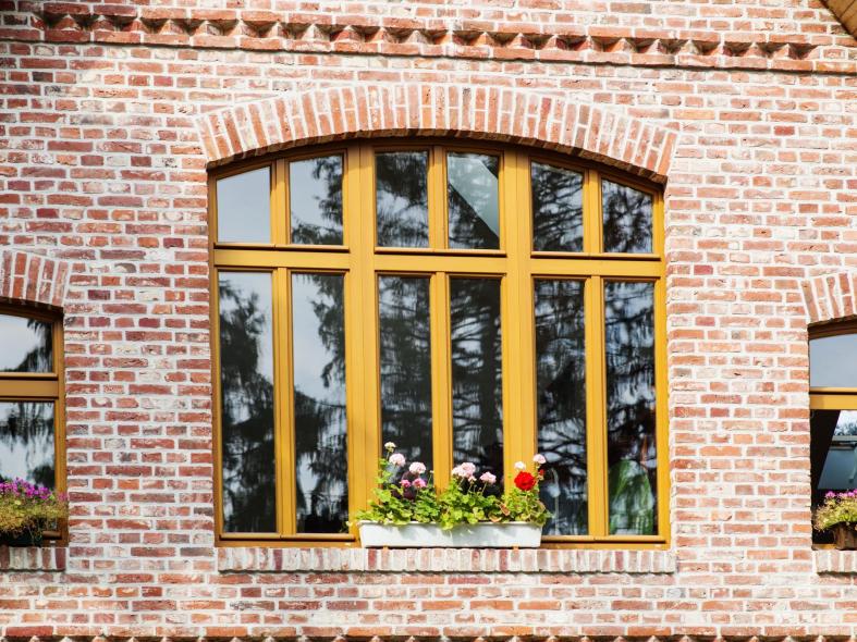 Großes mehrteiliges Holzfenster mit Stichbogen in Klinkerfassade eines historischen Bauernhauses in Schneverdingen