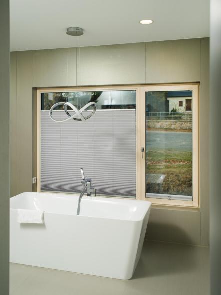 Die kalkweiß lasierten Holz-Aluminium Fenster im Badezimmer strahlen behagliche Wärme aus