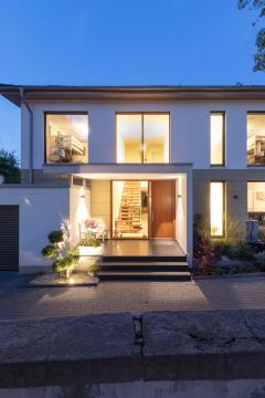 Die Stadtvilla mit Holz-Aluminium-Fenstern und Holzhaustür von PaX im Abendlicht